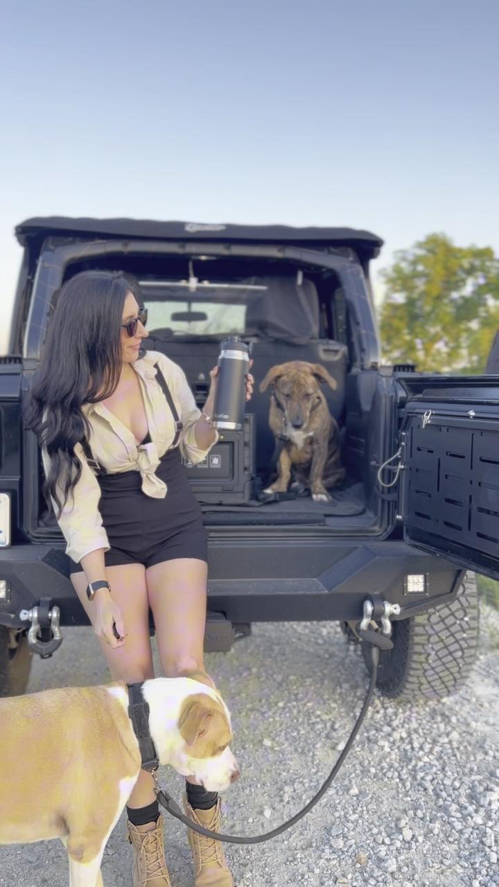 Tati at the back of her Jeep with a tumbler and her two dogs
