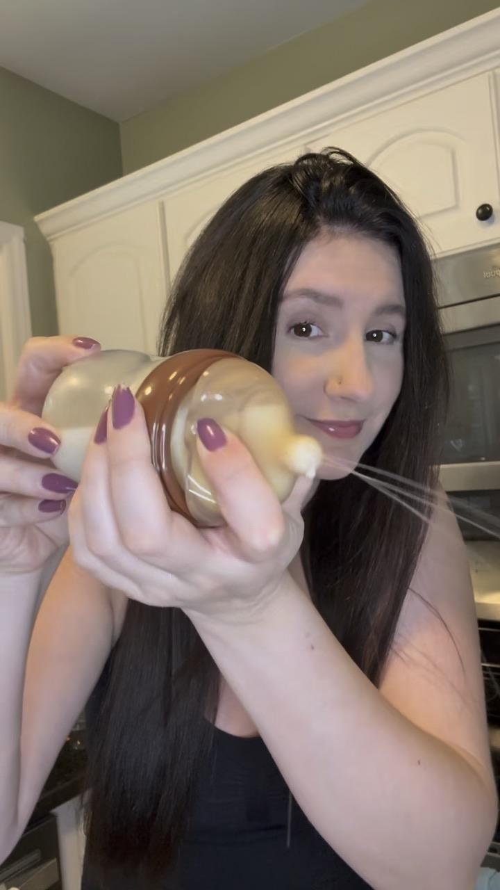 Tati in her kitchen holding a baby bottle during a product demo
